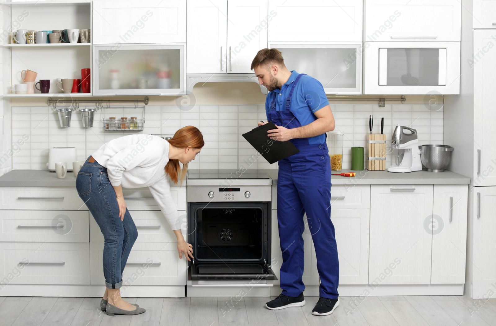 Photo of Housewife with repairman near modern oven in kitchen