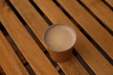 Takeaway paper cup with coffee on wooden table