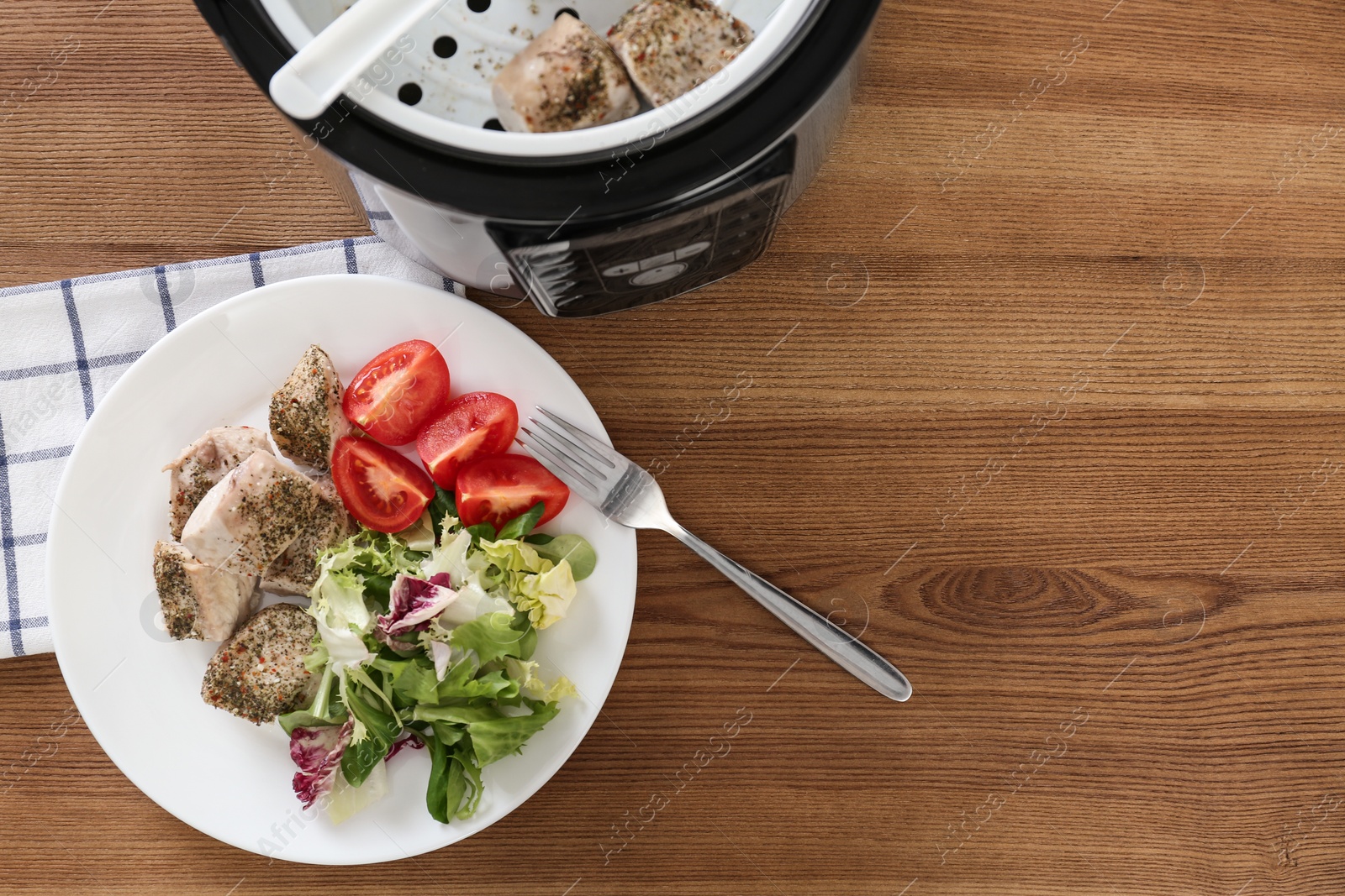 Photo of Delicious chicken with vegetables and modern multi cooker on wooden table, flat lay. Space for text