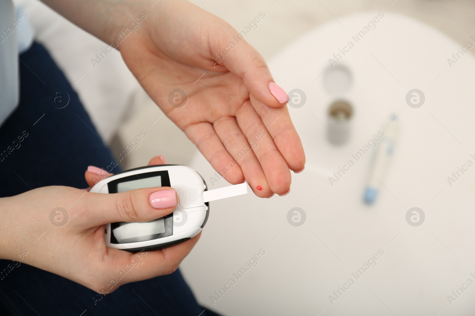 Photo of Diabetes. Woman checking blood sugar level with glucometer at home, above view
