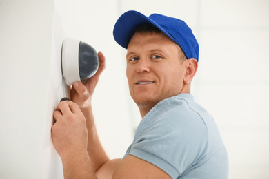 Photo of Technician installing CCTV camera on wall indoors