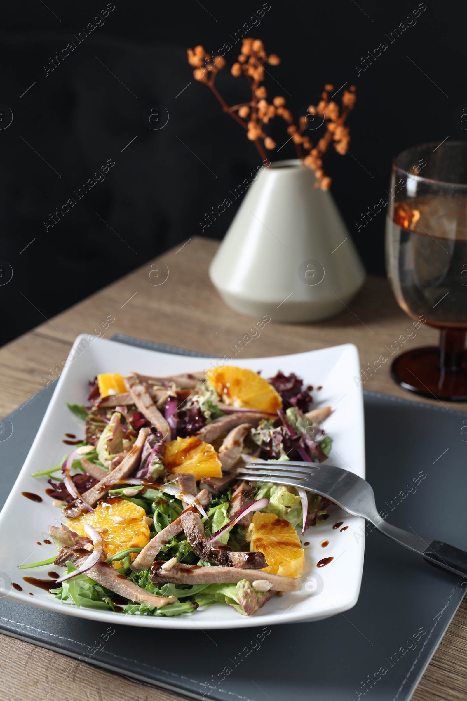 Photo of Delicious salad with beef tongue, orange, onion and fork served on wooden table