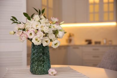 Photo of Bouquet of beautiful flowers on table in kitchen, space for text. Interior design