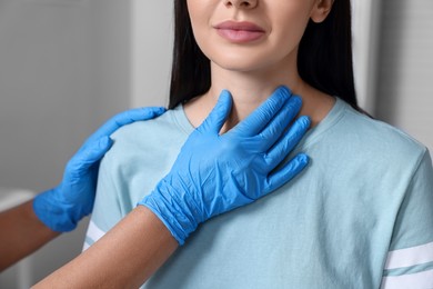 Photo of Endocrinologist examining thyroid gland of patient indoors, closeup