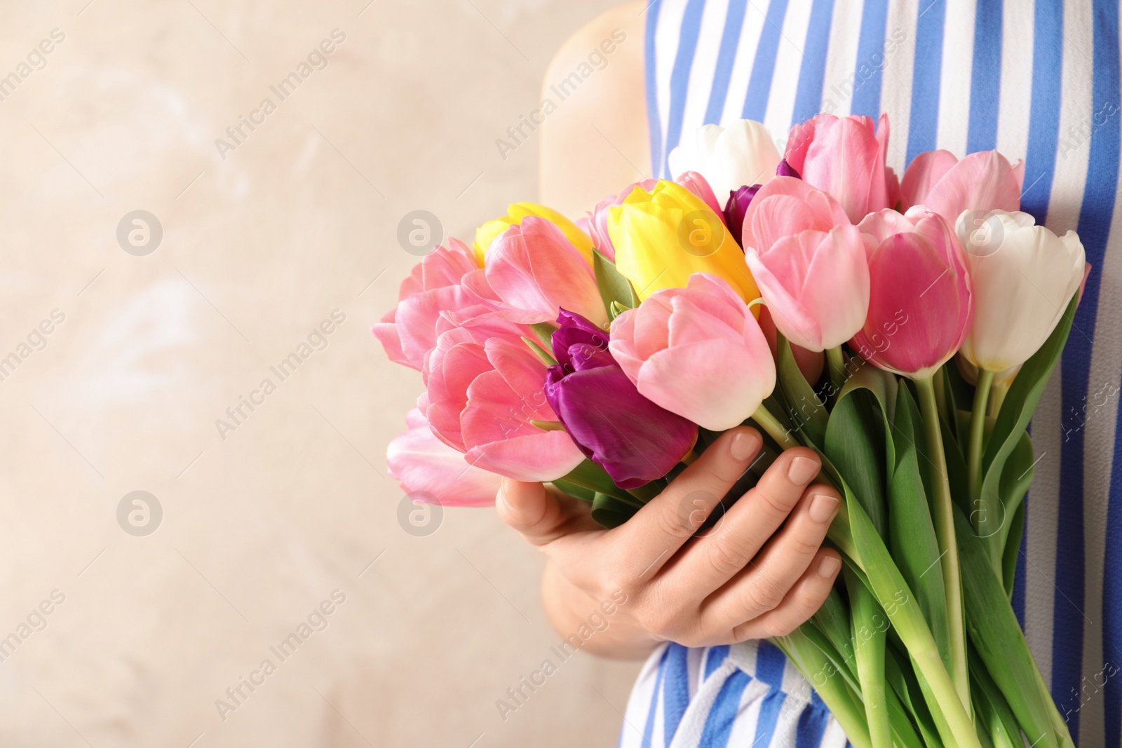 Photo of Girl holding bouquet of beautiful spring tulips on color background, closeup with space for text. International Women's Day