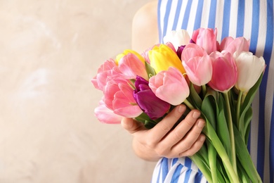 Photo of Girl holding bouquet of beautiful spring tulips on color background, closeup with space for text. International Women's Day