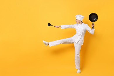 Professional chef with wok and spatula having fun on yellow background