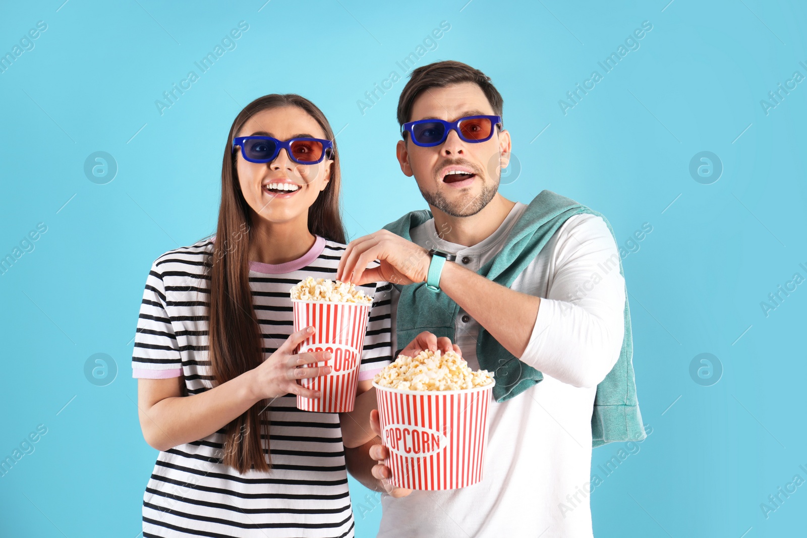 Photo of Couple with 3D glasses and tasty popcorn on color background