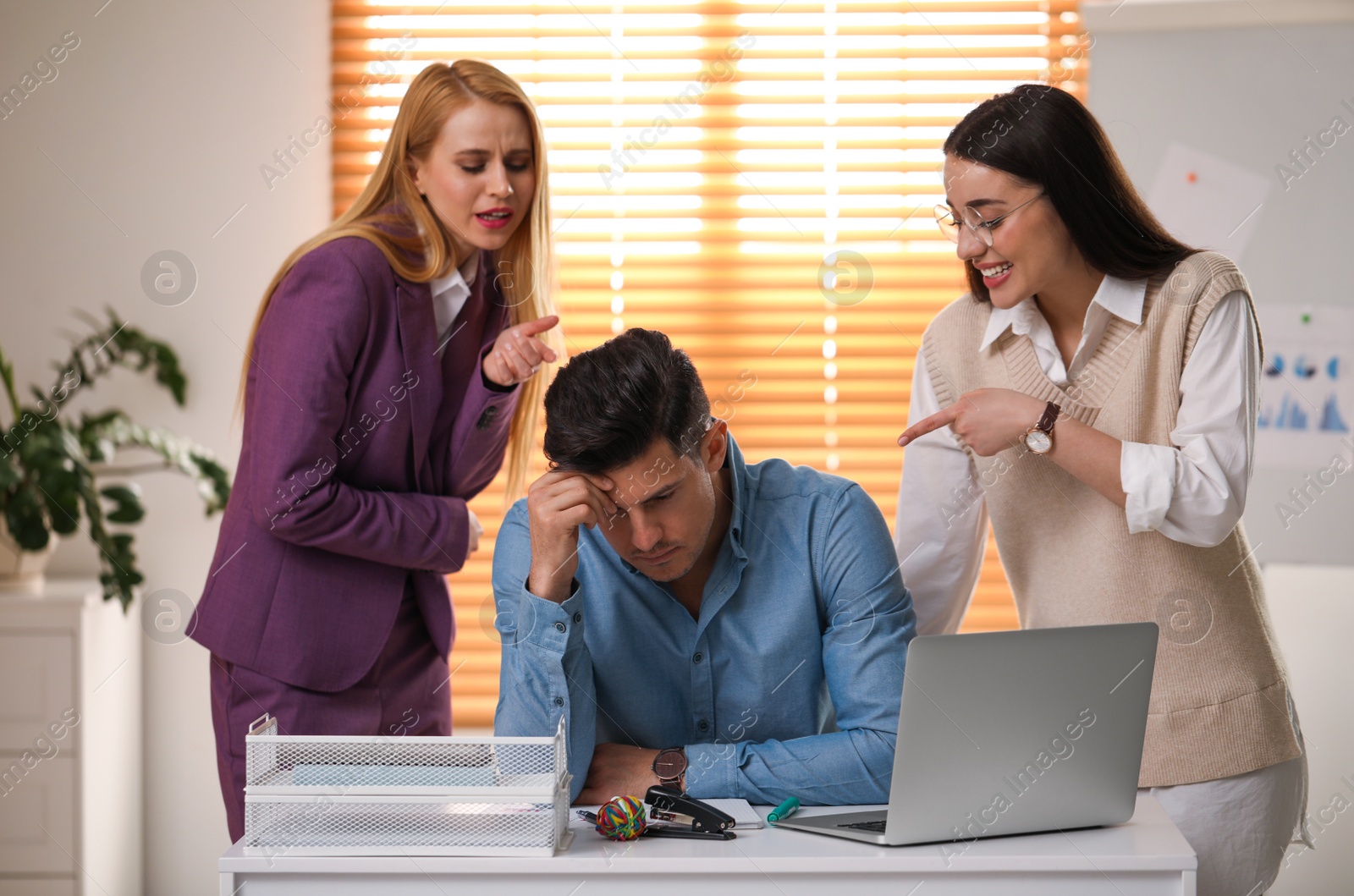 Photo of Coworkers bullying their colleague at workplace in office