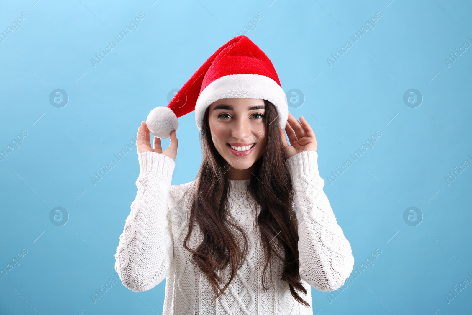 Photo of Beautiful woman wearing Santa Claus hat on light blue background