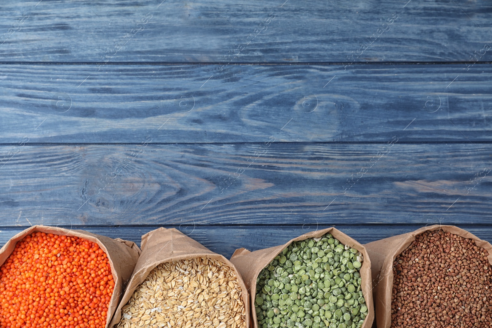 Photo of Flat lay composition with different types of legumes and cereals on blue wooden table, space for text. Organic grains