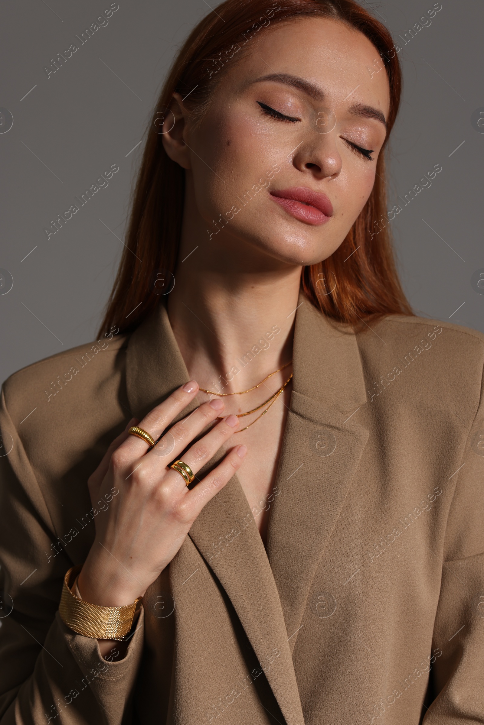 Photo of Beautiful young woman with elegant jewelry on gray background