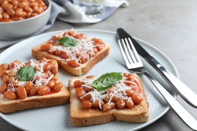 Toasts with delicious canned beans on light grey table