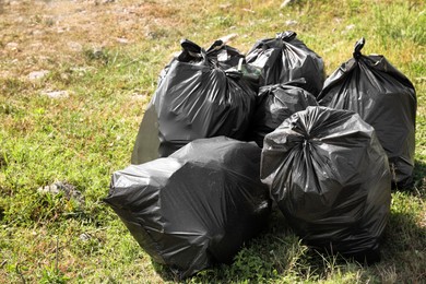 Photo of Many trash bags full of garbage on green grass outdoors. Environmental Pollution concept