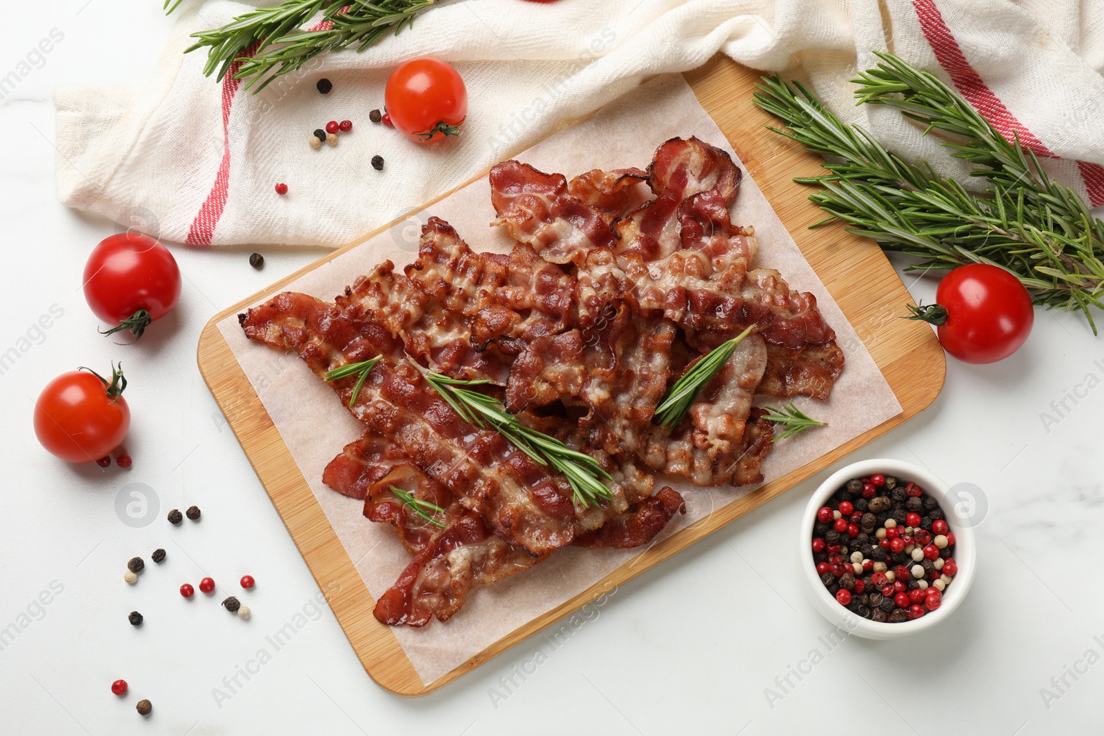 Photo of Slices of tasty fried bacon with different spices and tomatoes on light table, flat lay