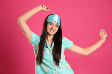 Photo of Beautiful woman wearing sleeping mask on pink background. Bedtime