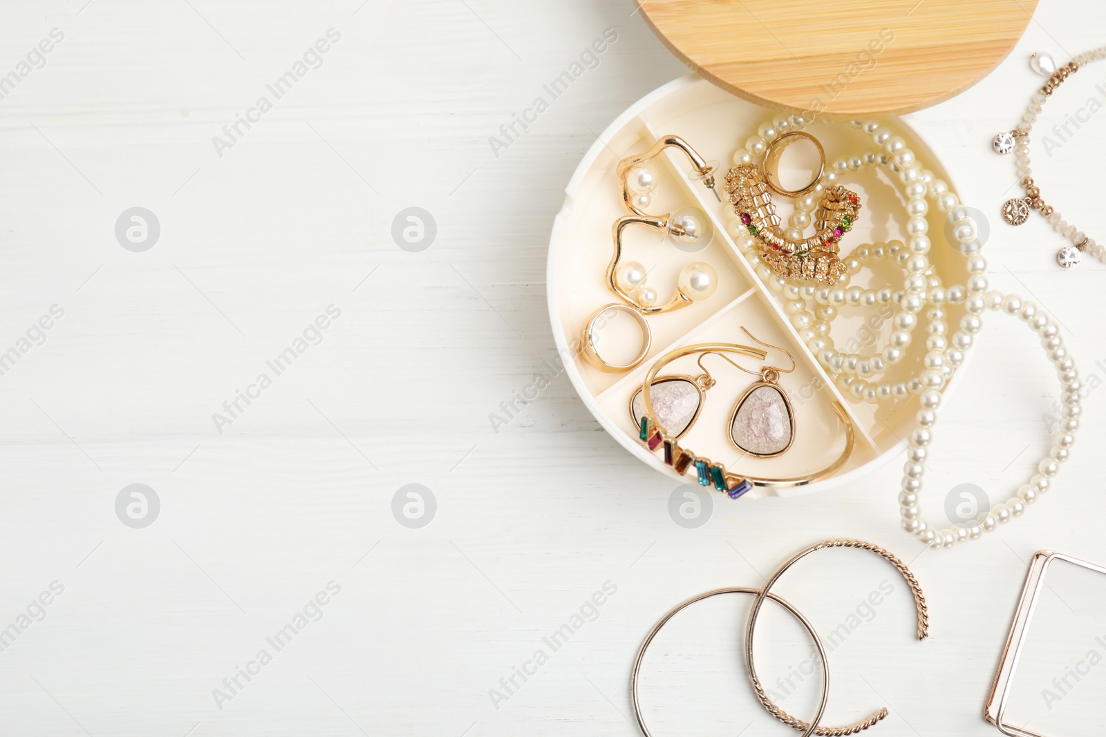 Photo of Jewelry box with stylish bijouterie on white wooden table, flat lay Space for text