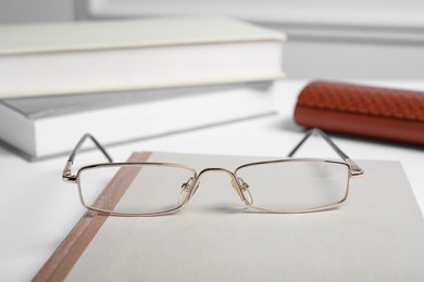 Photo of Stylish pair of glasses with metal frame on white table, closeup