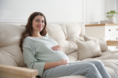 Photo of Happy pregnant woman touching her belly indoors