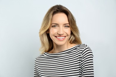 Photo of Portrait of happy young woman with beautiful blonde hair and charming smile on light background