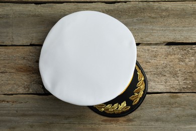 Peaked cap with accessories on wooden background, top view