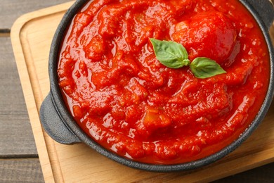 Homemade tomato sauce and basil in bowl on wooden table