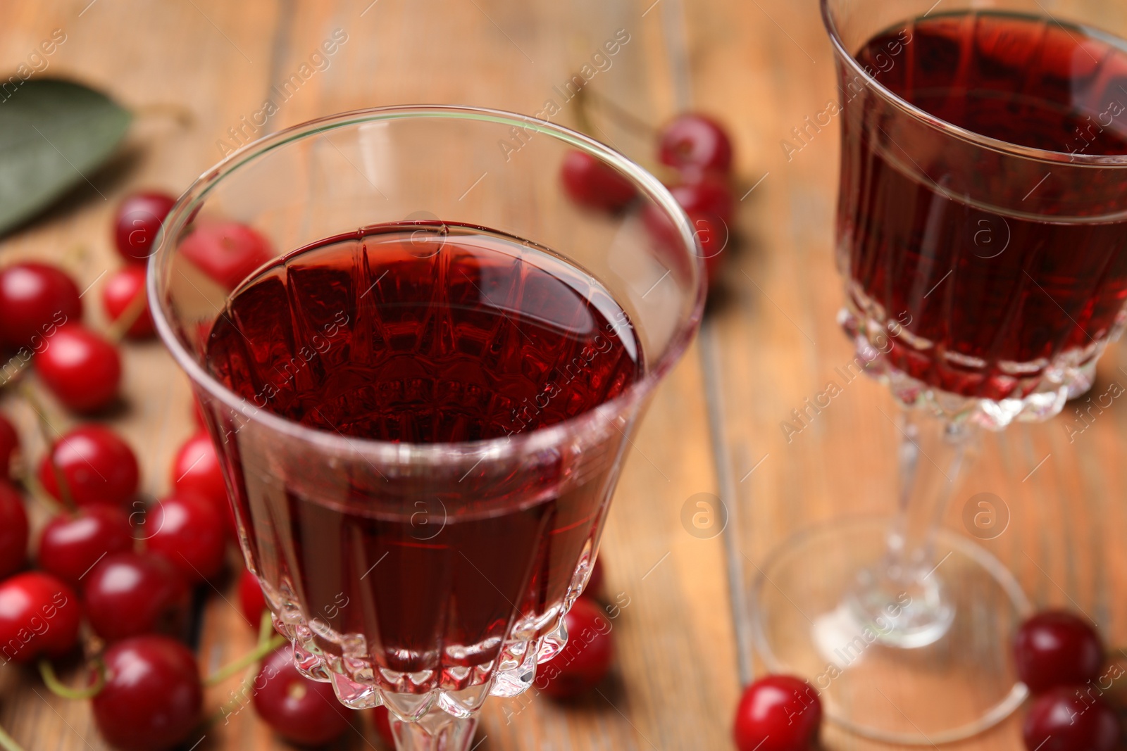 Photo of Delicious cherry wine with ripe juicy berries on wooden table, closeup
