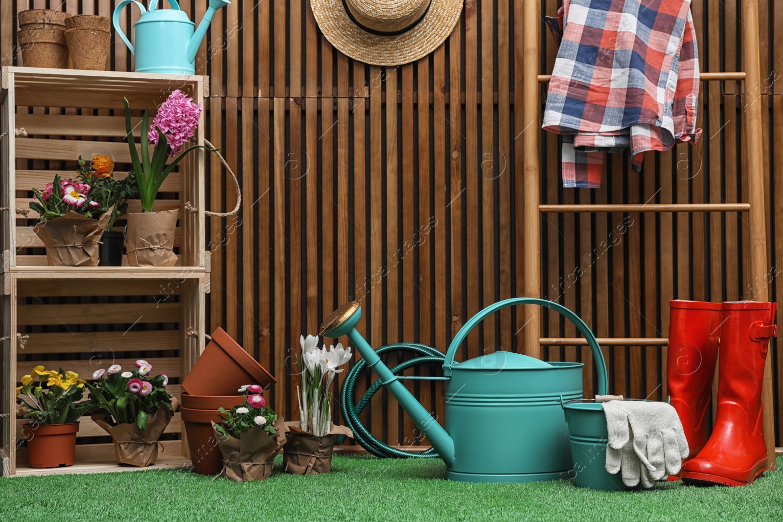 Photo of Composition with different gardening tools on artificial grass at wooden wall. Space for text