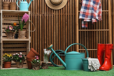 Composition with different gardening tools on artificial grass at wooden wall. Space for text