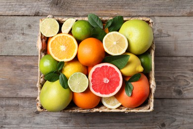 Photo of Different cut and whole citrus fruits on wooden table, top view