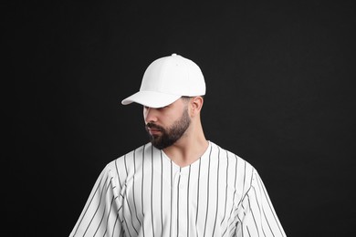 Photo of Man in stylish white baseball cap on black background