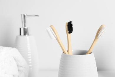 Photo of Bamboo toothbrushes in holder on blurred background, closeup. Space for text