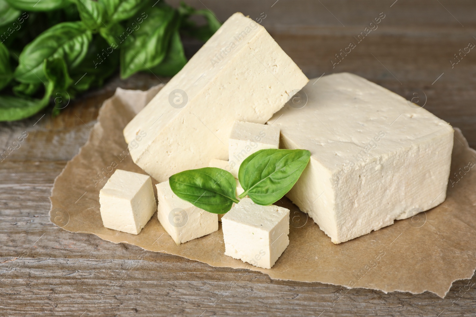 Photo of Delicious tofu with basil on wooden table