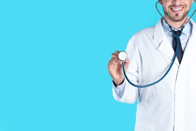 Photo of Male doctor holding stethoscope on color background, closeup with space for text