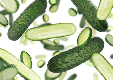 Image of Fresh green cucumbers falling on white background