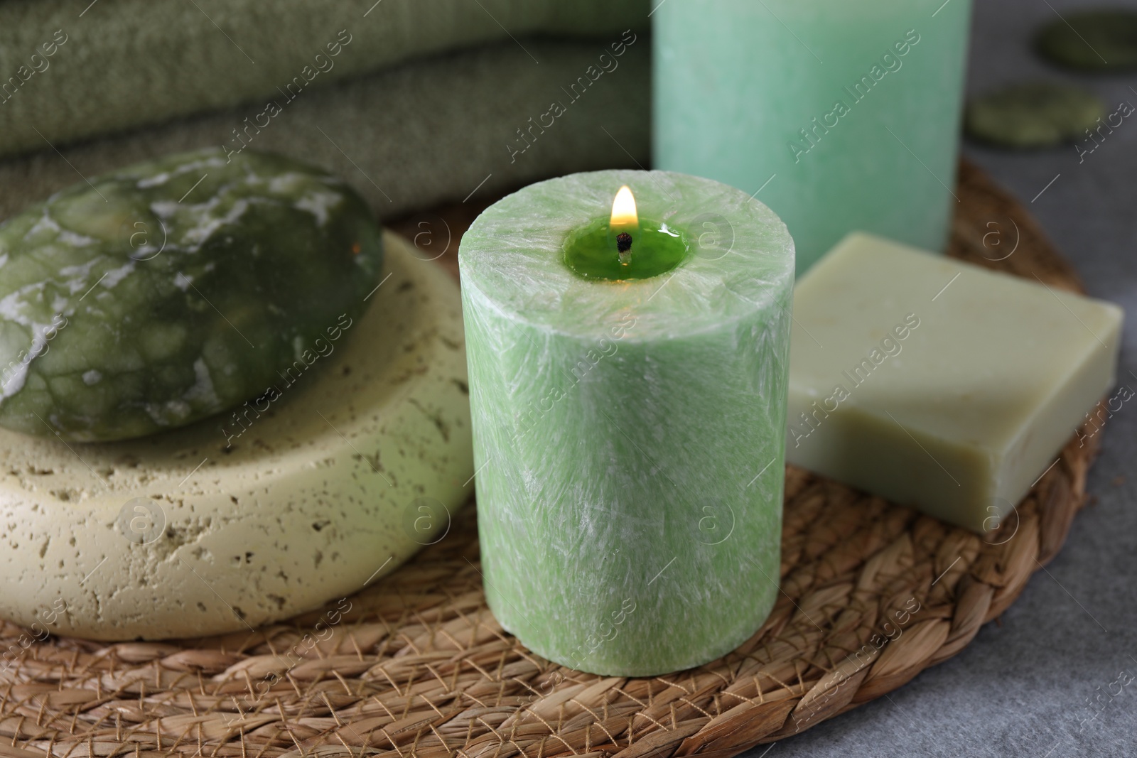 Photo of Spa composition. Burning candle, stone and soap on grey table