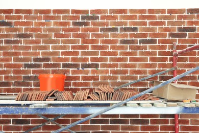 Photo of Scaffolding near wall with decorative bricks and tile leveling system indoors