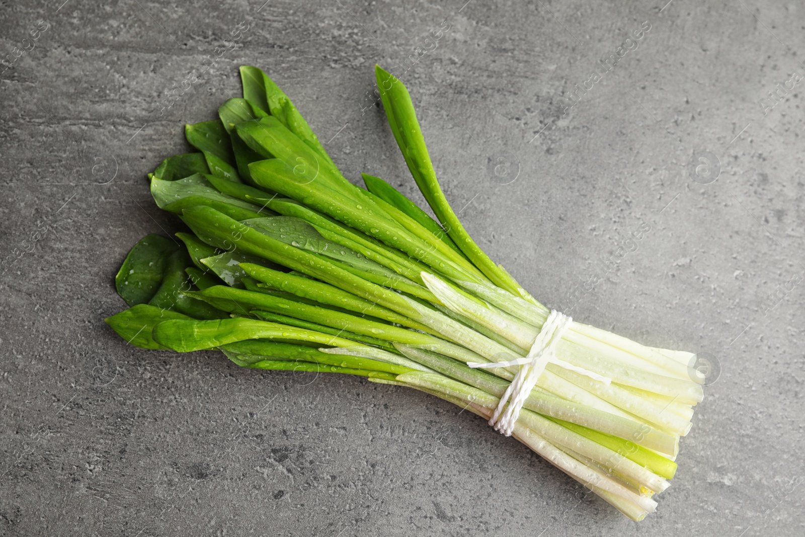 Photo of Bunch of wild garlic or ramson on grey table, top view