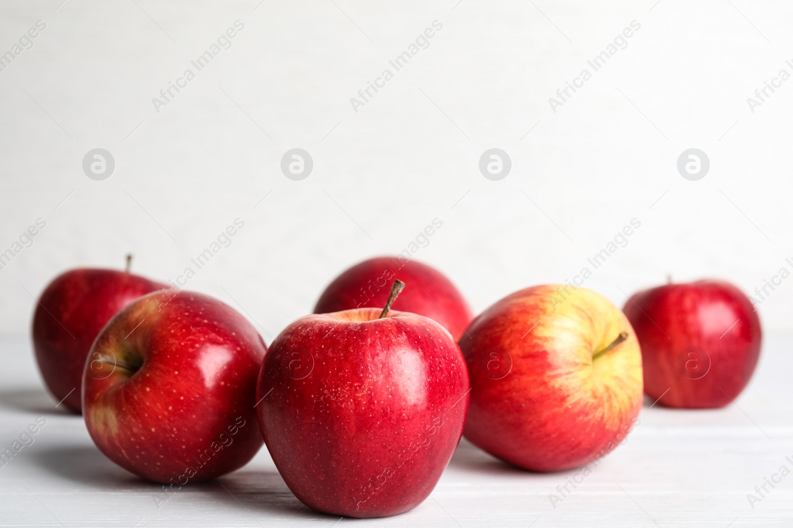 Photo of Ripe red apples on white wooden table. Space for text