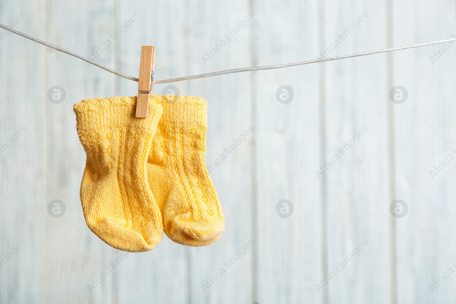 Photo of Baby socks on laundry line against wooden background, space for text. Child accessories