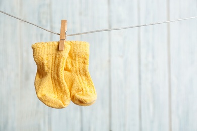 Photo of Baby socks on laundry line against wooden background, space for text. Child accessories