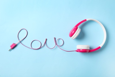 Photo of Word Love made with cable of headphones on light blue background, top view. Listening music songs 