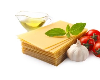 Photo of Stack of uncooked lasagna sheets, tomatoes, oil and garlic isolated on white