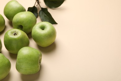 Photo of Fresh green apples and leaves on beige background, above view. Space for text