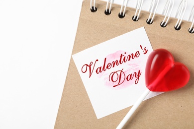 Image of Happy Valentine's Day. Heart shaped lollipop, notebook and paper note with lipstick kiss on white background, flat lay