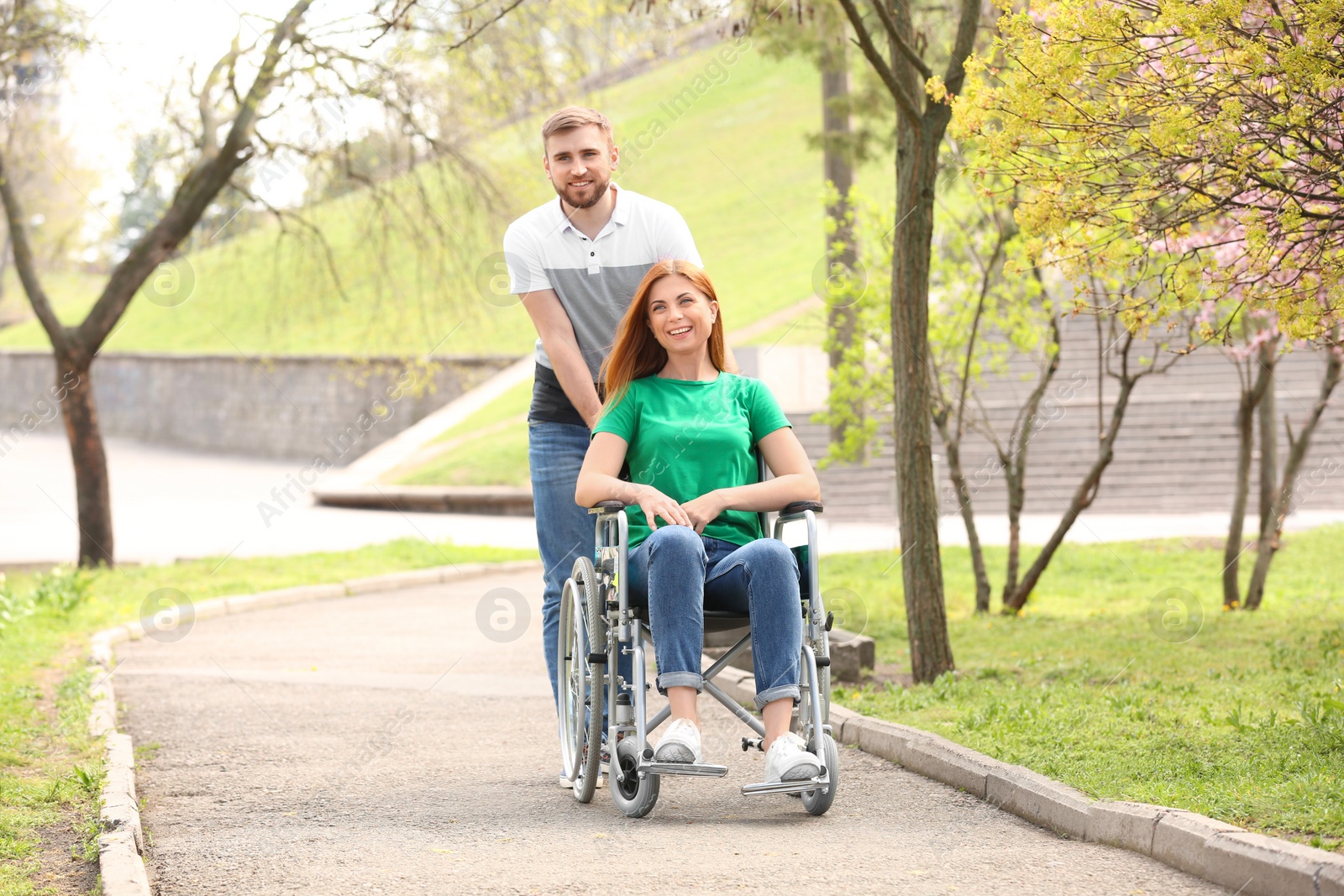 Photo of Happy woman in wheelchair and young man at park on sunny day