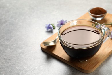 Glass cup of delicious chicory drink on light grey table, closeup. Space for text