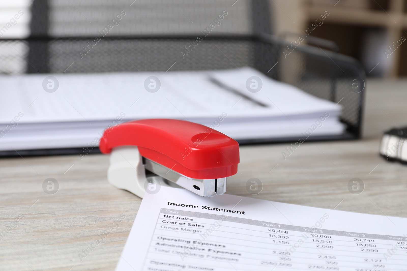 Photo of Stapler with document on wooden table, closeup