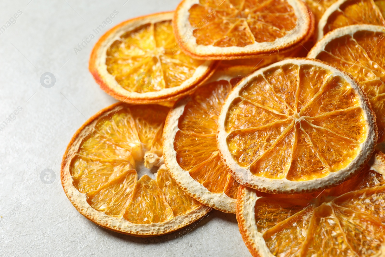 Photo of Heap of dry orange slices on light grey table, closeup