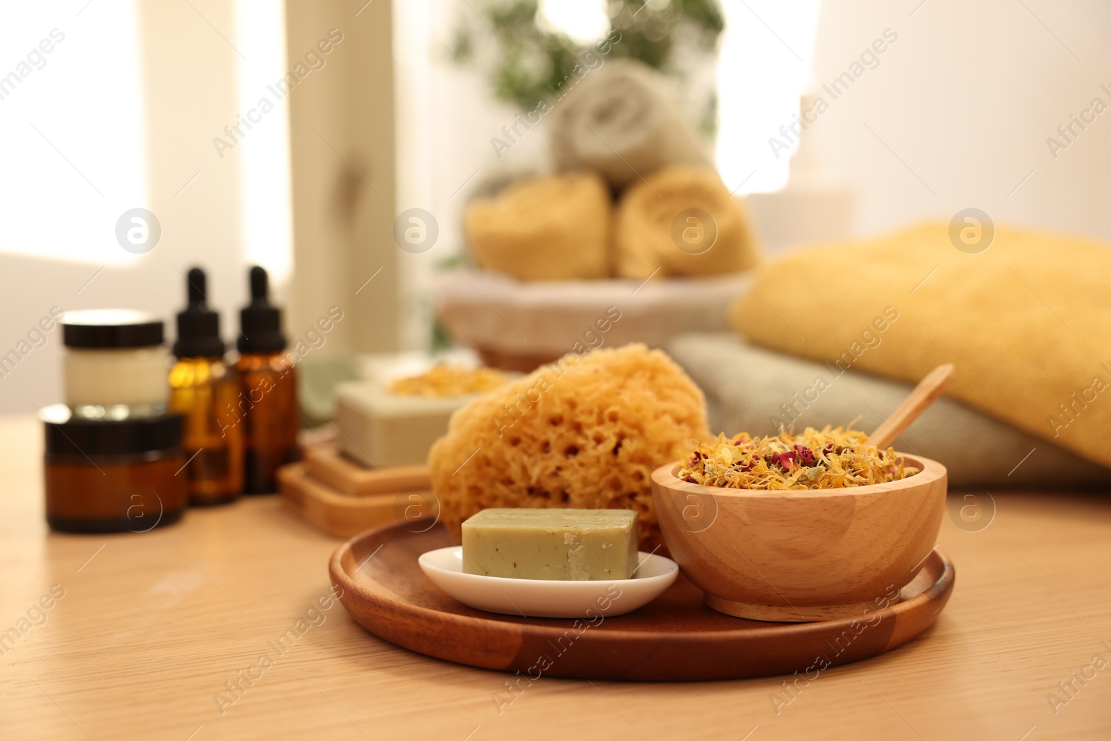 Photo of Dry flowers, loofah and soap bar on wooden table indoors. Spa time